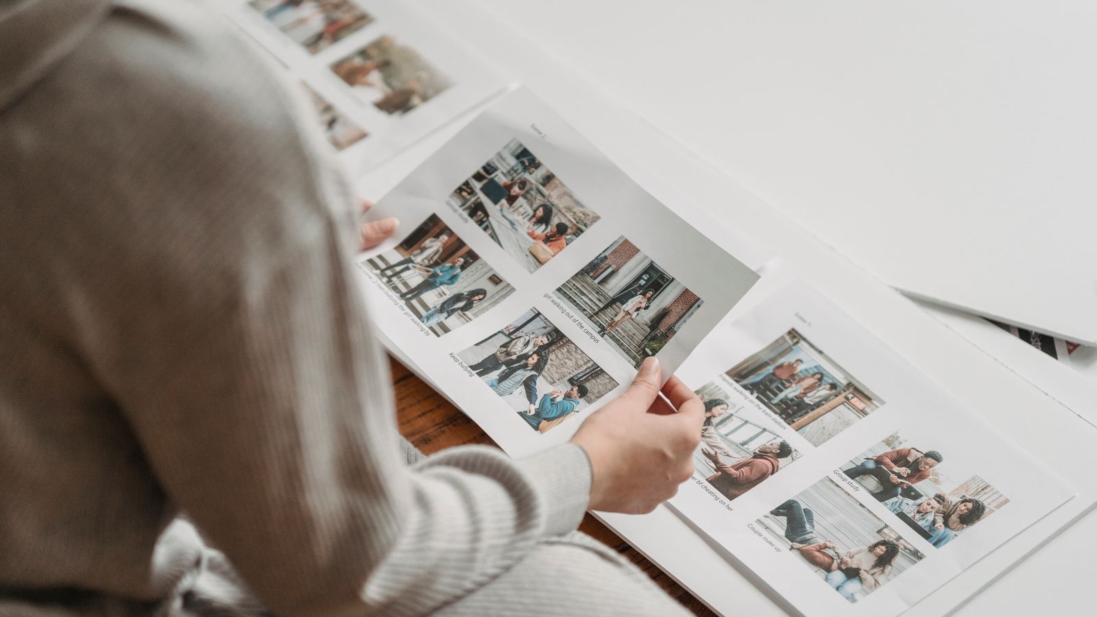 Handen van een ouder die een teleurstellend fotoalbum openslaan op een houten tafel, met zacht daglicht vanuit een raam