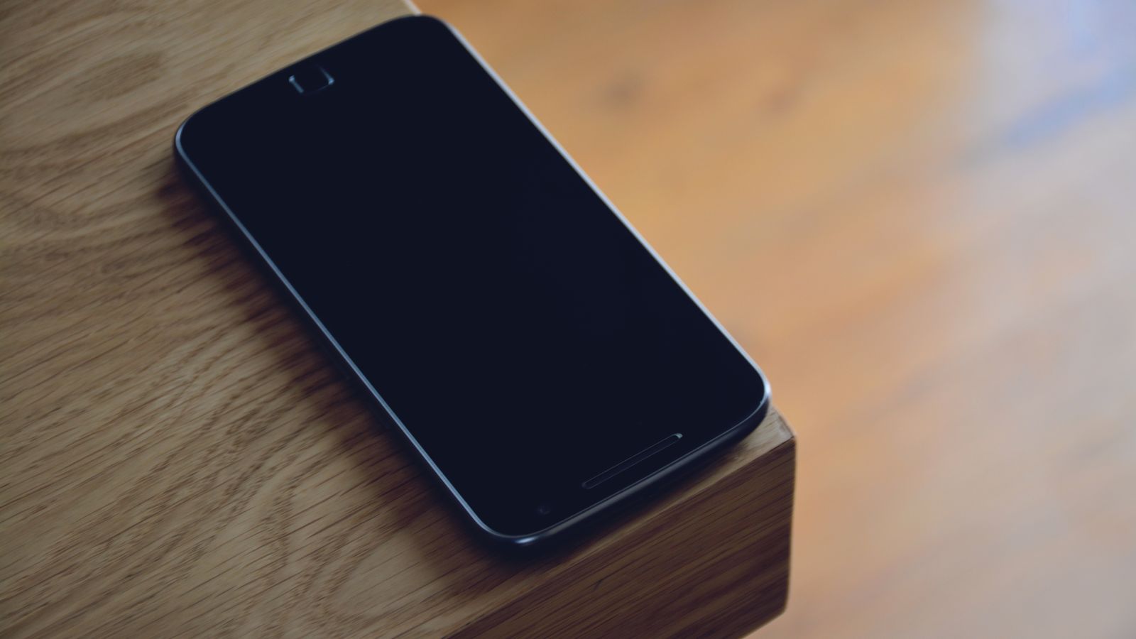 Een smartphone ligt open op een houten tafel naast een kopje koffie, zacht ochtendlicht valt door een raam op het scherm